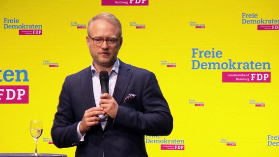 Hamburgs FDP-Landesvorsitzender Michael Kruse spricht in ein Mikrofon, im Hintergrund FDP-Werbung. © Screenshot 