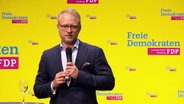 Hamburgs FDP-Landesvorsitzender Michael Kruse spricht in ein Mikrofon, im Hintergrund FDP-Werbung. © Screenshot 