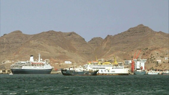 Schiffe liegen an einem Hafen vor Einer Berglandschaft © Screenshot 