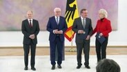 Bundeskanzler Olaf Scholz, Bundespräsiden Frank Walter Steinmeier, die alte Verteidigungsministerin Christine Lambrecht und der neue Verteidigungsminister Boris Piustorius stehen auf einer Bühne. © Screenshot 