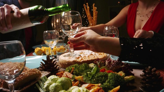 An einem gedeckten Tisch wird Wein eingeschenkt. © Screenshot 