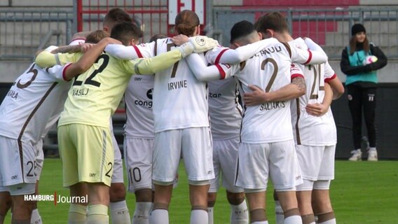 Fußballer des FC St. Pauli stehen in einem Kreis zusammen. © Screenshot 