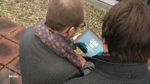 zwei Studierende sitzen auf einer Bank an einem Tablet © Screenshot 