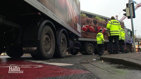 Nach einem Verkehrsunfall sichern Verkehrspolizisten die Unfallstelle ab an der ein zweigliedriger Lkw nach rechts abgebogen ist. © Screenshot 