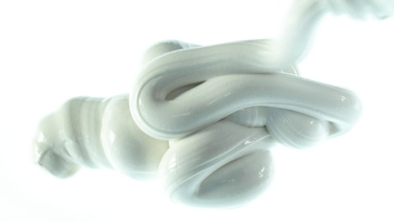 Eine weiße Zahnpasta-Wurst auf weißem Hintergrund. © Screenshot 