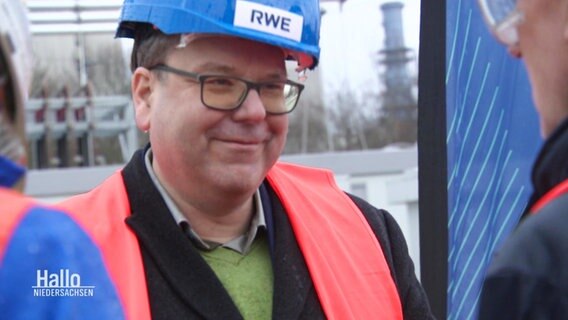 Christian Meyer, Niedersachsens Umwelt- und Energieminister von den Grünen, trägt bei einer Werksbegehung eine rote Warnweste und einen blauen Helm mit der Aufschrift "RWE". © Screenshot 