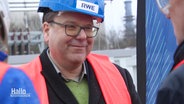 Christian Meyer, Niedersachsens Umwelt- und Energieminister von den Grünen, trägt bei einer Werksbegehung eine rote Warnweste und einen blauen Helm mit der Aufschrift "RWE". © Screenshot 