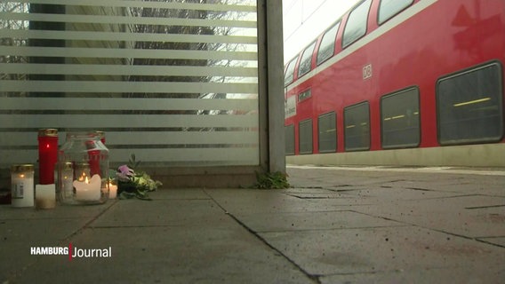 Eine kleine Gedenkstätte mit Kerzen und Blumen auf dem Gelis eines Bahnhofes © Screenshot 