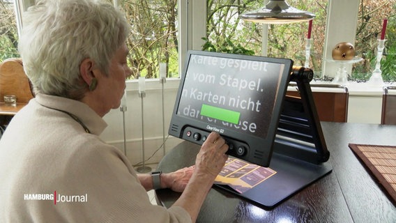 Eine Frau sitzt vor einem Monitor, auf dem sehr große Buchstaben abgebildet sind. © Screenshot 