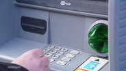 Eine Hand vor der Bedienungsfläche eines Geldautomaten © Screenshot 