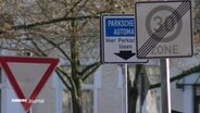 Zwischen zwei Straßenschildern steht ein Schild, das auf einen Parkscheinautomat hinweist. © Screenshot 