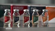 Verschiedene Impf-Ampullen stehen aufgereiht auf einem Tisch © Screenshot 
