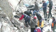 In den trümmern eines durch ein Erdbeben eingestürzten Gebäudes suchen mehrere Menschen nach Überlebenden. © Screenshot 