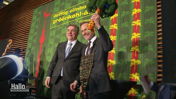 Finanzminister Lindner auf einer Bühne mit einem Strauß Grünkohl in der Hand. © Screenshot 