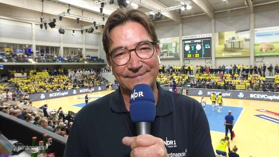 Ein Reporter ist zu sehen, dahinter ein Volleyballfeld. © Screenshot 