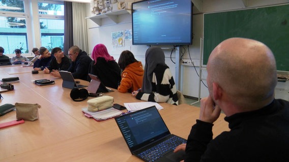 Eine Schulklasse schaut in einem Klassenzimmer auf einen Bildschirm. © Screenshot 