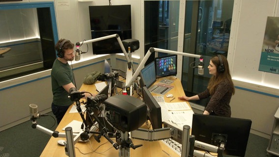 Zwei Menschen, rechts eine Frau, links ein Mann in einem Hörfunkstudio bei einem Interview; Benjamin Fredrich und Carolin Kock. © Screenshot 