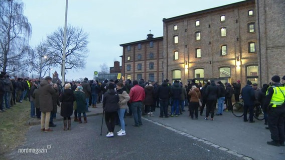 A crowd of people in front of a brick building © Screenshot 