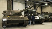 Zwei Personen betrachten die ausgestellten Panzer im Panzermuseum. © Screenshot 