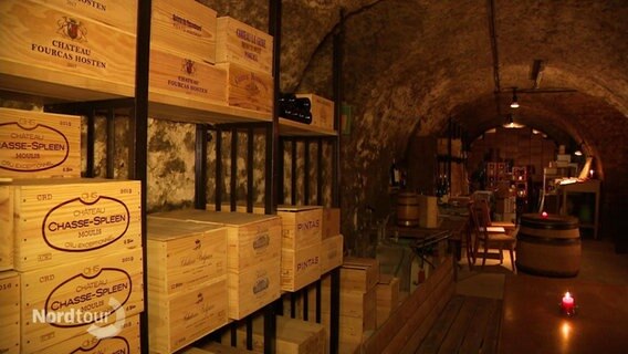 In einem Weinkeller reihen sich Regale und Kisten ann den Wänden © Screenshot 