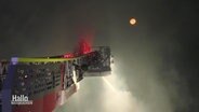 Ein Leiterwagen löscht Feuer, im Hintergrund der Mond. Von unten steigt Rauch auf. © Screenshot 