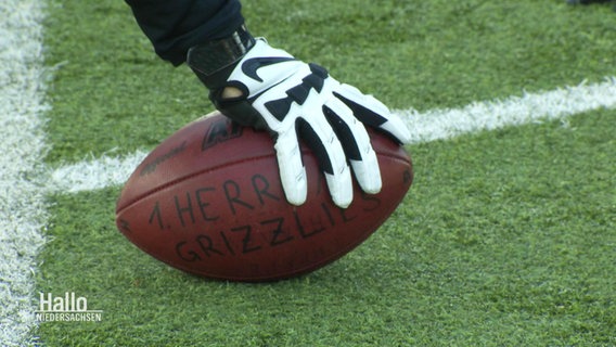 Eine Hand mit einem Handschuh drückt einen Football auf den Boden. © Screenshot 