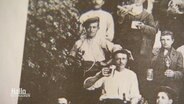 Eine historische Fotografie zeigt mehrere Männer mit einem Getränk in der Hand. © Screenshot 