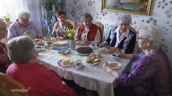Eine Gruppe von Seniorinnen sitzen um einen Tisch und essen Kuchen © Screenshot 