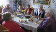 Eine Gruppe von Seniorinnen sitzen um einen Tisch und essen Kuchen © Screenshot 