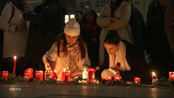 Zwei Frauen entzünden Kerzen auf einer Gedenkveranstaltung auf dem hamburger rathausmarkt © Screenshot 