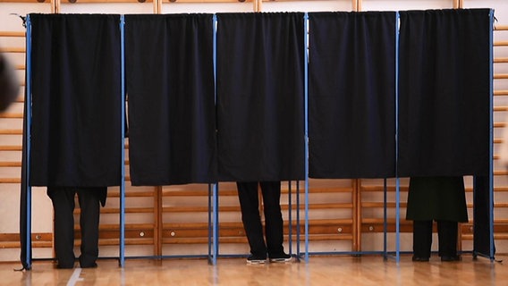 Drei Personen stehen in Wahlkabinen. © Screenshot 