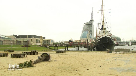 Blick auf die Bremerhavener Strandpromenade mit einem Kutter und einem größeren Hochaus in der Ferne. © Screenshot 