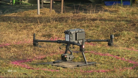 Eine Drohne landet auf einer Grasfläche innerhalb einer echteckigen, roten Markierung. © Screenshot 