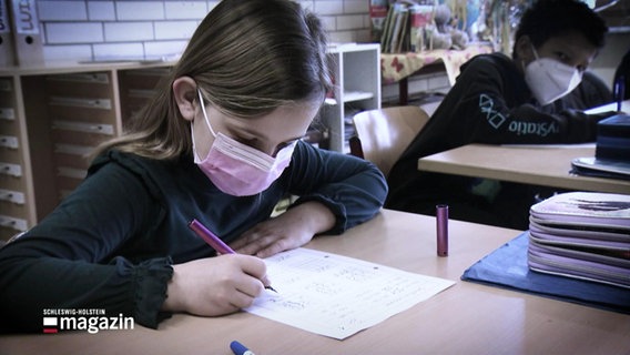 Ein kind mit medizinischer maske schreibt an einem Tisch © Screenshot 