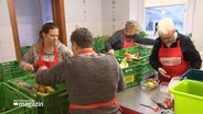 Vier Frauen stehen an grünen Plastikkisten und sortieren Lebensmittel für die Tafel in Bad Schwartau. © Screenshot 