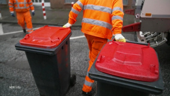 Ein Mitarbeiter der Müllreinigung zieht zwei Mülltonnen hinter sich her © Screenshot 