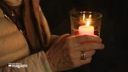 Eine Seniorin hält eine Kerze © Screenshot 
