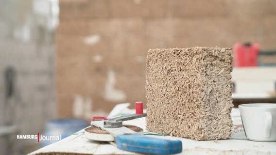 Ein Block aus Bau-Hanf liegt auf einer Arbeitsfläche einer Baustelle für ein Wohnhaus. © Screenshot 