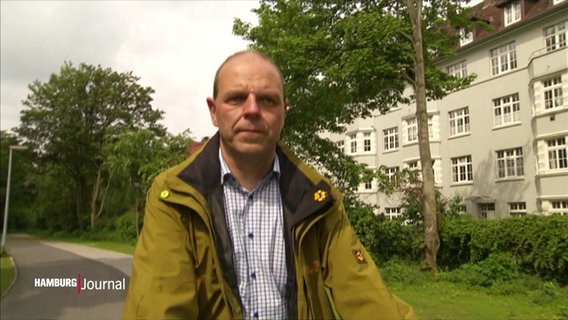 Der ehemalige Hamburger Grünen-Politiker Michael Osterburg geht auf einem Wanderweg neben einem Wohnhaus. © Screenshot 