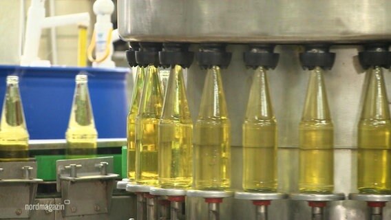 Glasflaschen auf einem Laufband werden in einer Mosterei mit Apfelsaft gefüllt © Screenshot 