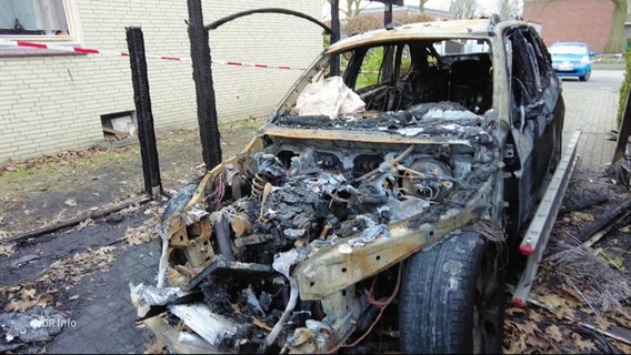 DAs ausgebrannte Wrack eines Autos steht in der Einfahrt eines Privatgrundstücks. © Screenshot 