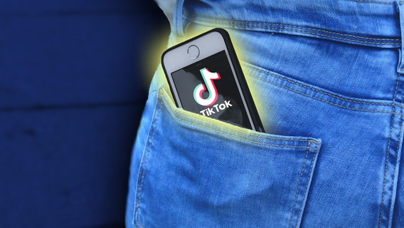 Auf einem Smartphone-Display in der Hosentasche ist das Logo von TikTok zu sehen. Der Spion in der Hosentasche. (Soziales Netzwerk TikTok: Grüße nach China! / extra 3 vom 23.02.2023 im Ersten) © NDR 