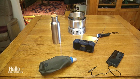 Hilfsmittel und Elektrogeräte, die bei einem Katastrophenfall nützlich sein können, liegen auf einem Küchentisch. © Screenshot 