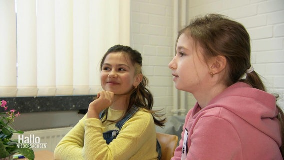 Zwei jüngere Mädchen sitzen in einem Schulbüro. © Screenshot 