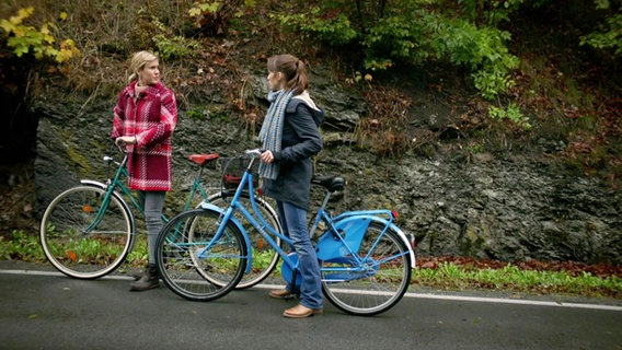 Zwei Frauen stehen mit ihren Fahrrädern am Straßenrand. © Screenshot 