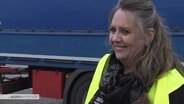 Die LKW-Dirigentin weist die LKWs ein. © Screenshot 