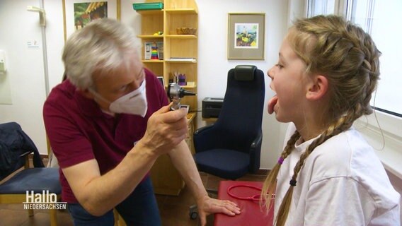 Ein Kinderarzt schaut einem Mädchen in den Mund. © Screenshot 