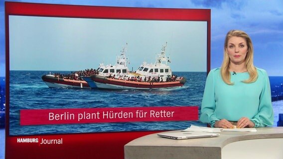 Nachrichtensprecherin Dina Hille im Studio, neben ihr das eingeblendete Bild eines Schiffes und eines Schlauchbootes im Mittelmeer mit Geflüchteten, darunter die Unterschrift: "Berlin plant Hürden für Retter". © Screenshot 