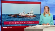 Nachrichtensprecherin Dina Hille im Studio, neben ihr das eingeblendete Bild eines Schiffes und eines Schlauchbootes im Mittelmeer mit Geflüchteten, darunter die Unterschrift: "Berlin plant Hürden für Retter". © Screenshot 