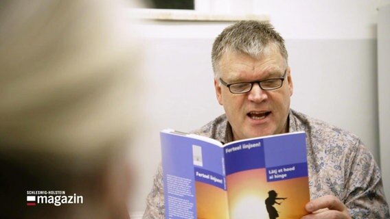 Mitglied des Nordfriesischen Vereins liest aus einem Buch vor. © Screenshot 
